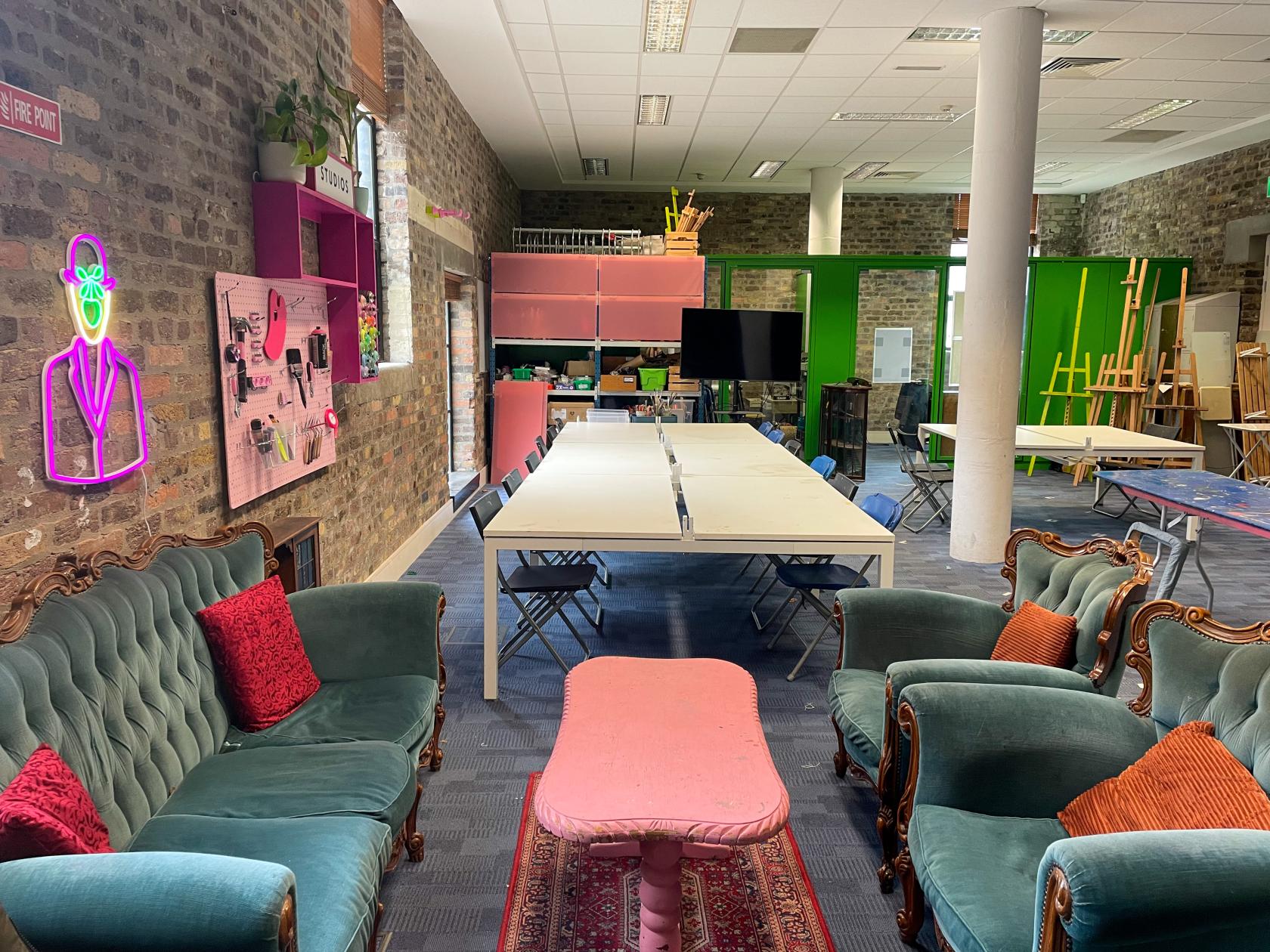 A creative space with exposed brick walls, long tables, vintage sofas, and art supplies at Flux Studios D8.
