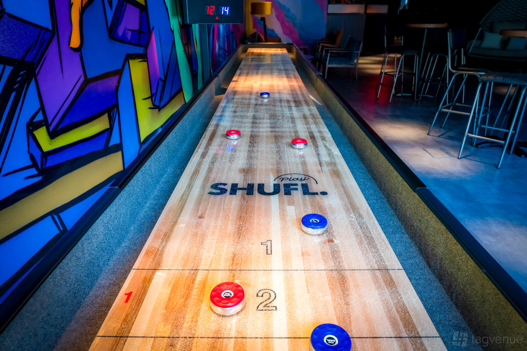 An entertainment centre event space with a shuffleboard table and colorful mural wall at The Light Redhill.