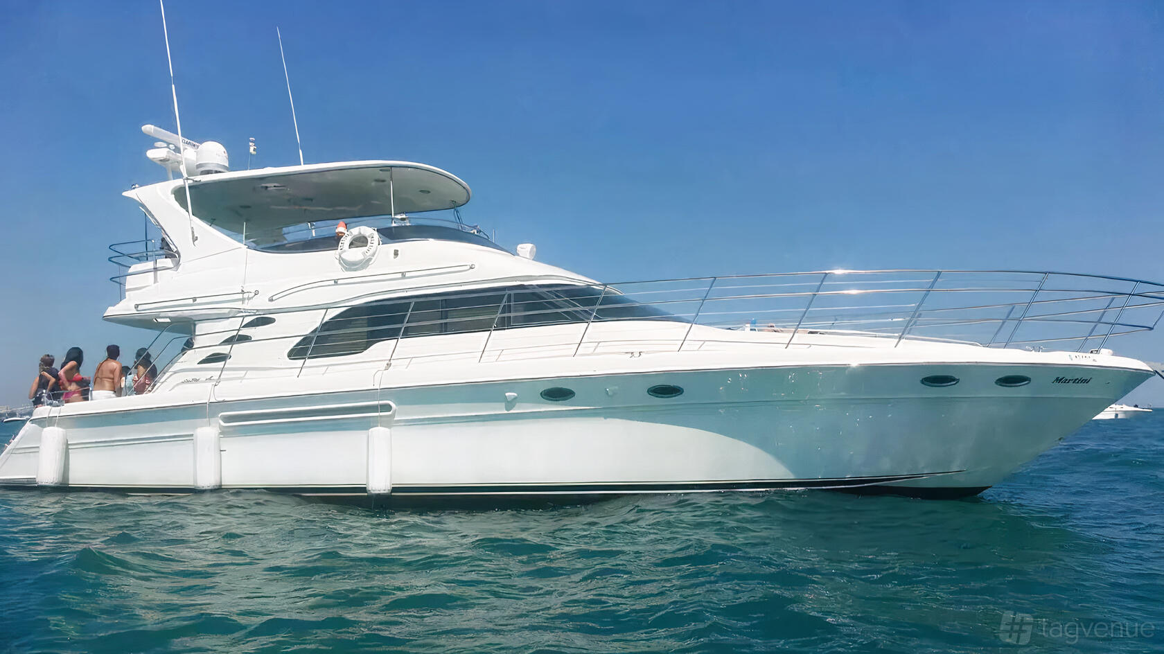A white yacht with an upper deck, railing, and guests on board on open water at Chicago Party Yacht.