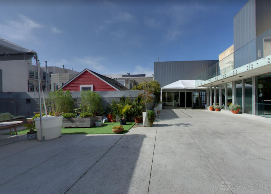An outdoor plaza with potted plants, concrete flooring, and adjacent modern glass-walled building at Congregation Beth Sholom.