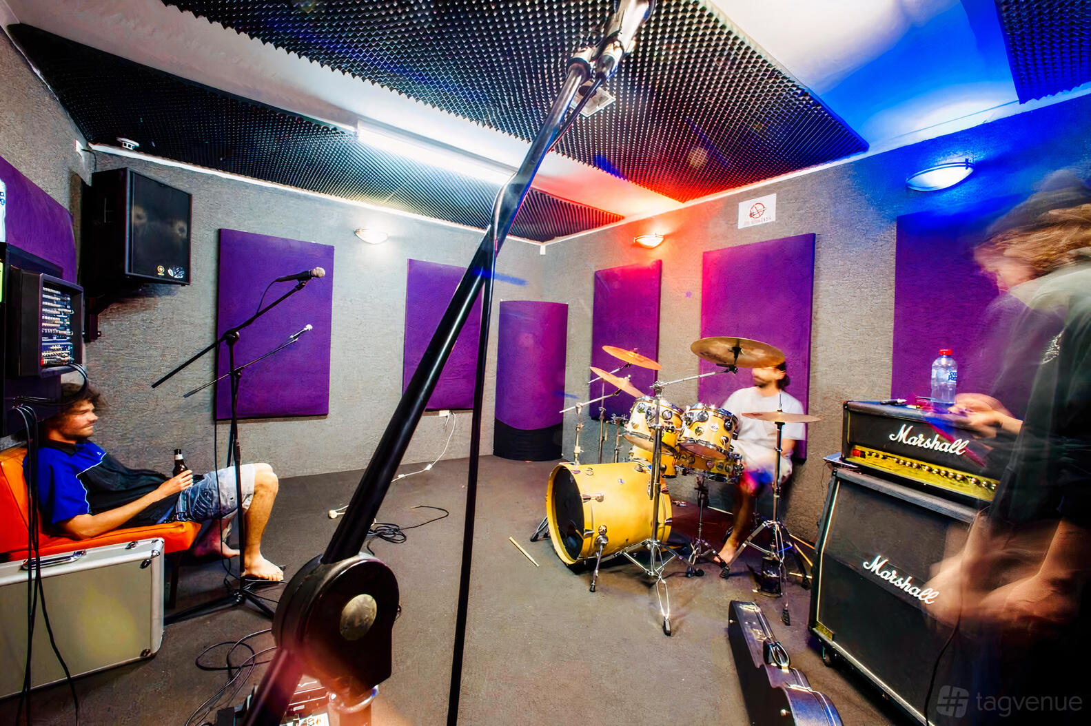 A rehearsal room with soundproofed walls, drum kit, amplifiers, and microphone stands at Bayside Rehearsal Studios.