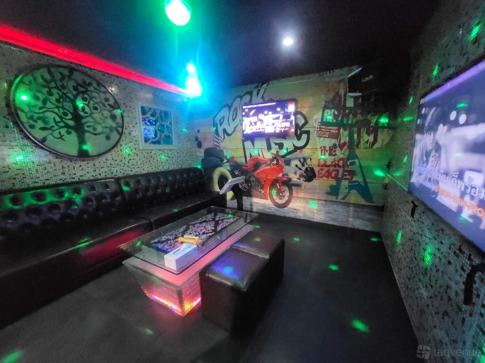 A karaoke bar room with leather seating, wall graffiti, a TV display, and disco lights at D1 Karaoke Sydney.