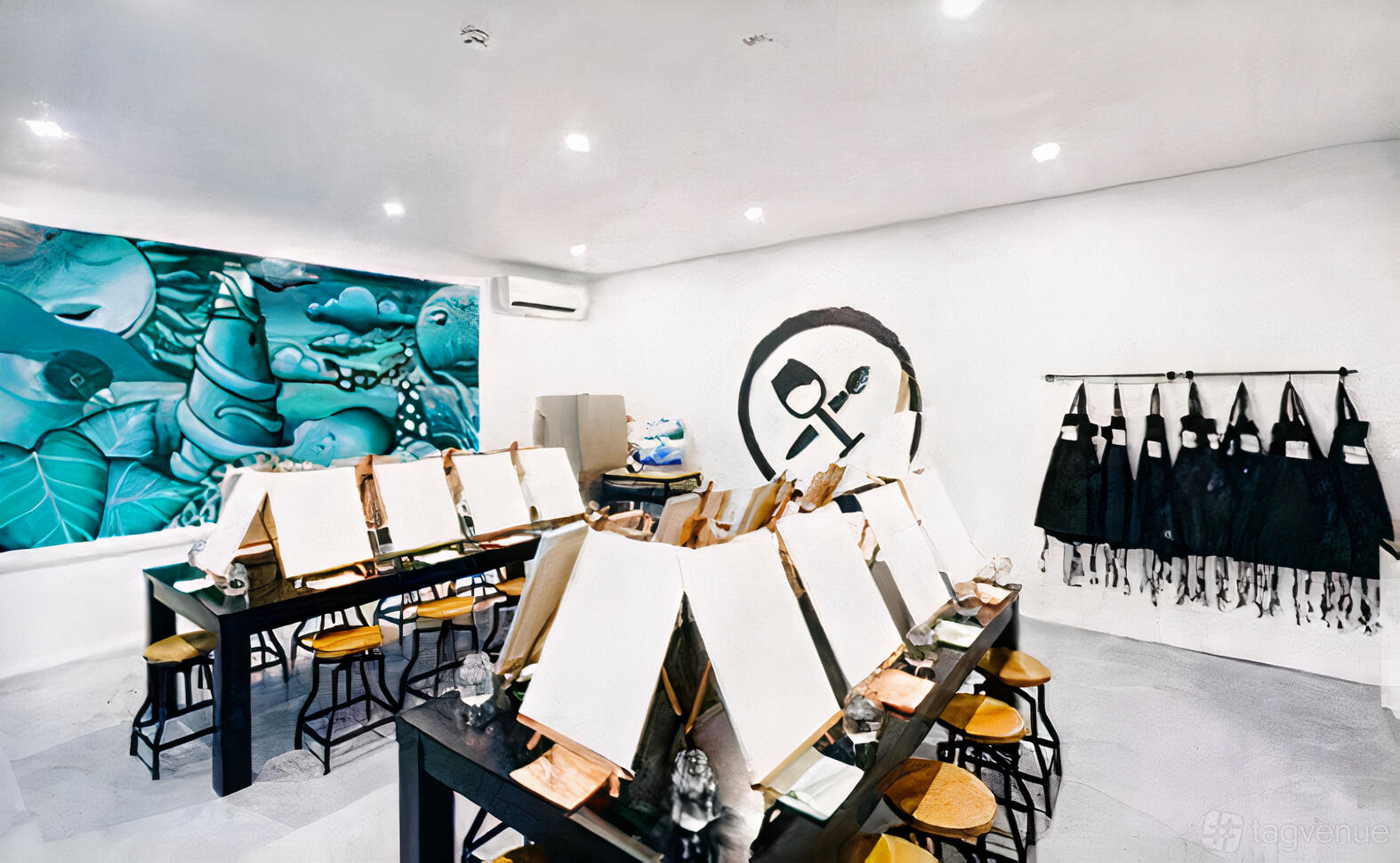 An event venue with easels set up on long tables, stools, apron racks, and mural art at Pinot & Picasso Redcliffe.