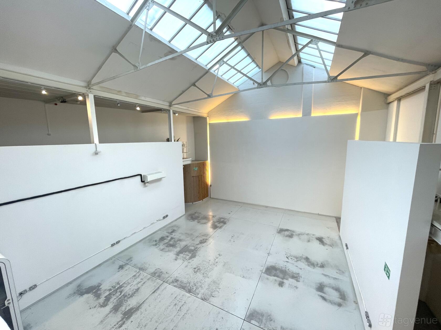 A coworking space with white walls, high ceilings, and overhead skylights at The Handbag Factory.