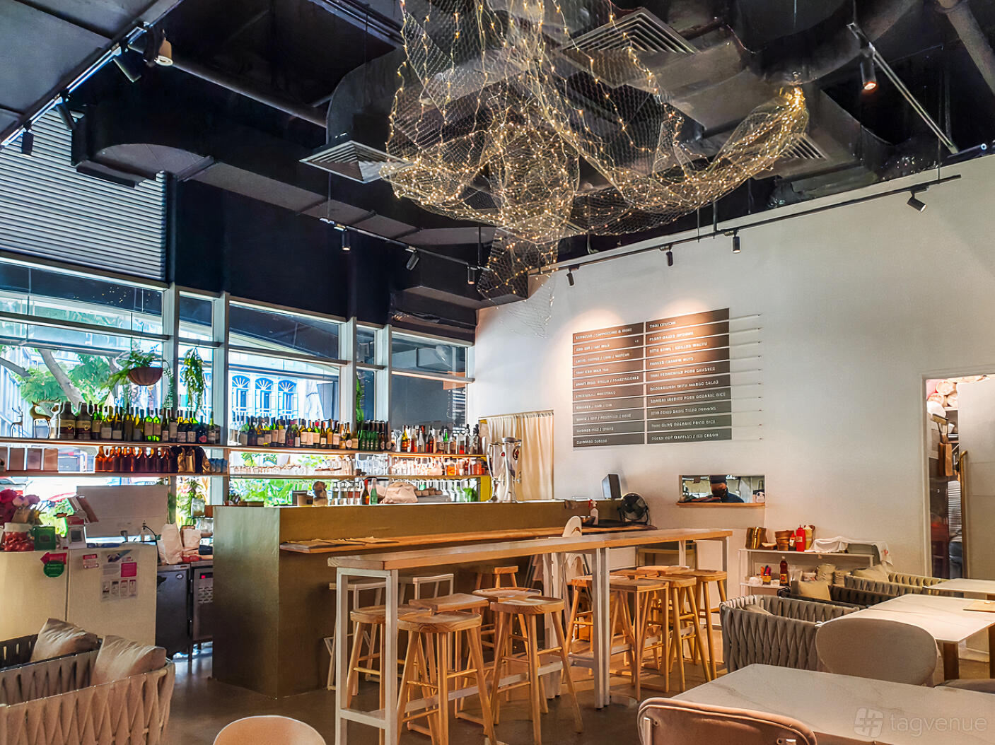 A restaurant with a wooden bar, high stools, and hanging string light decor at Vibez Bistro Bar.