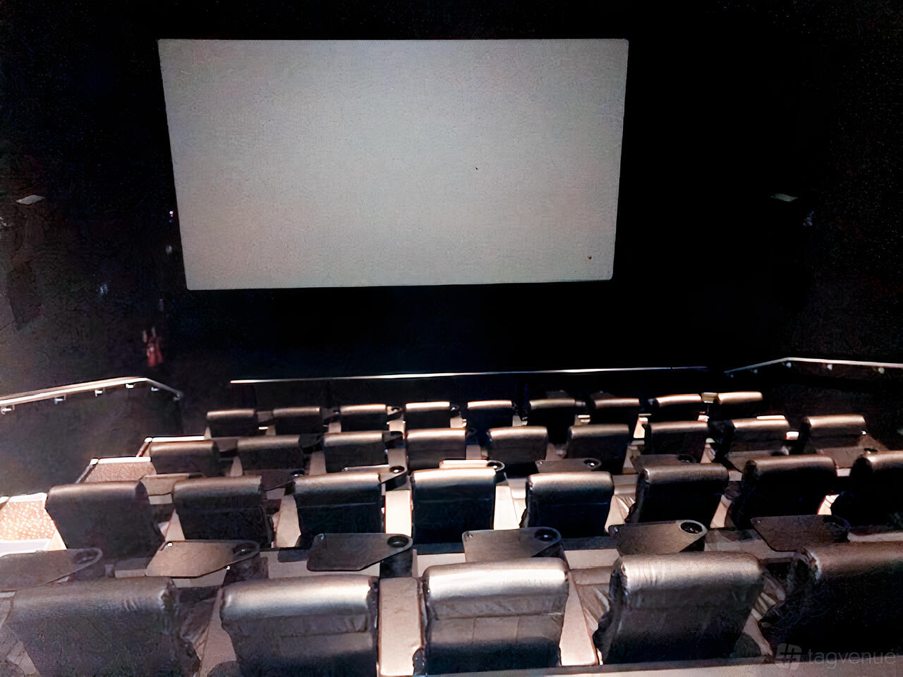 A cinema screening room with tiered leather seats, cup holders, and a large blank screen at Vue Manchester Quayside.