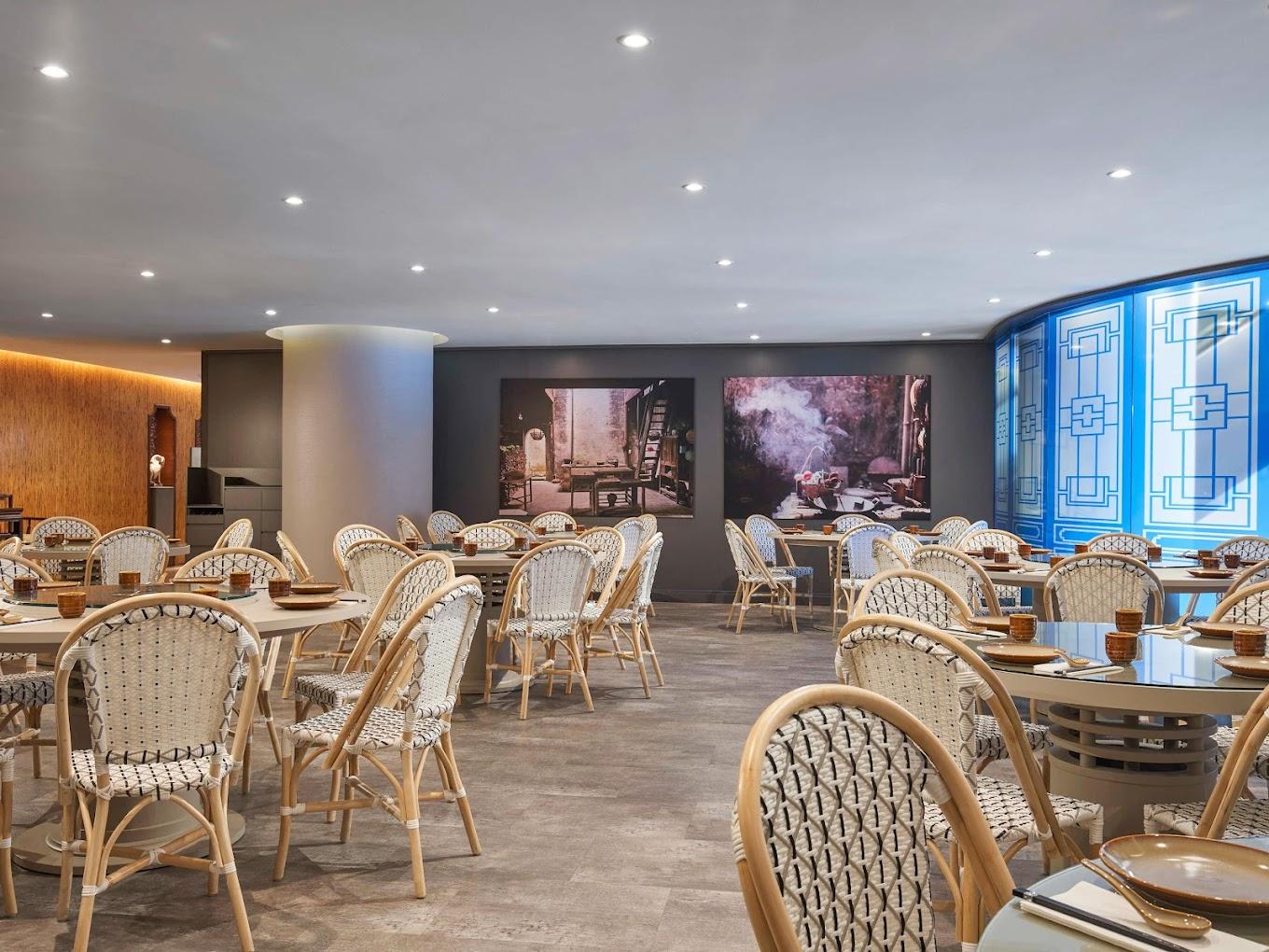 A restaurant with woven rattan chairs, wooden tables, and large wall art at Jia Wei Chinese Restaurant.