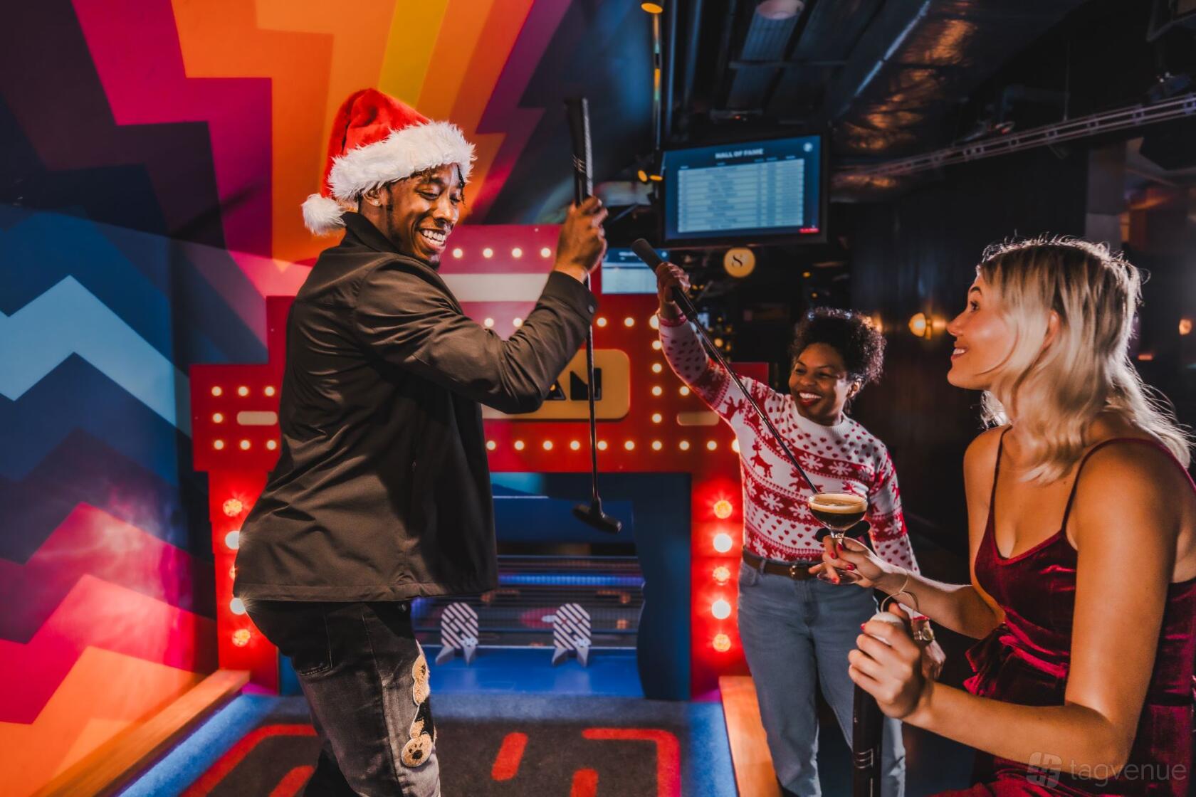 An event venue with colorful walls, mini-golf putting stations, and guests playing golf at Puttshack White City.
