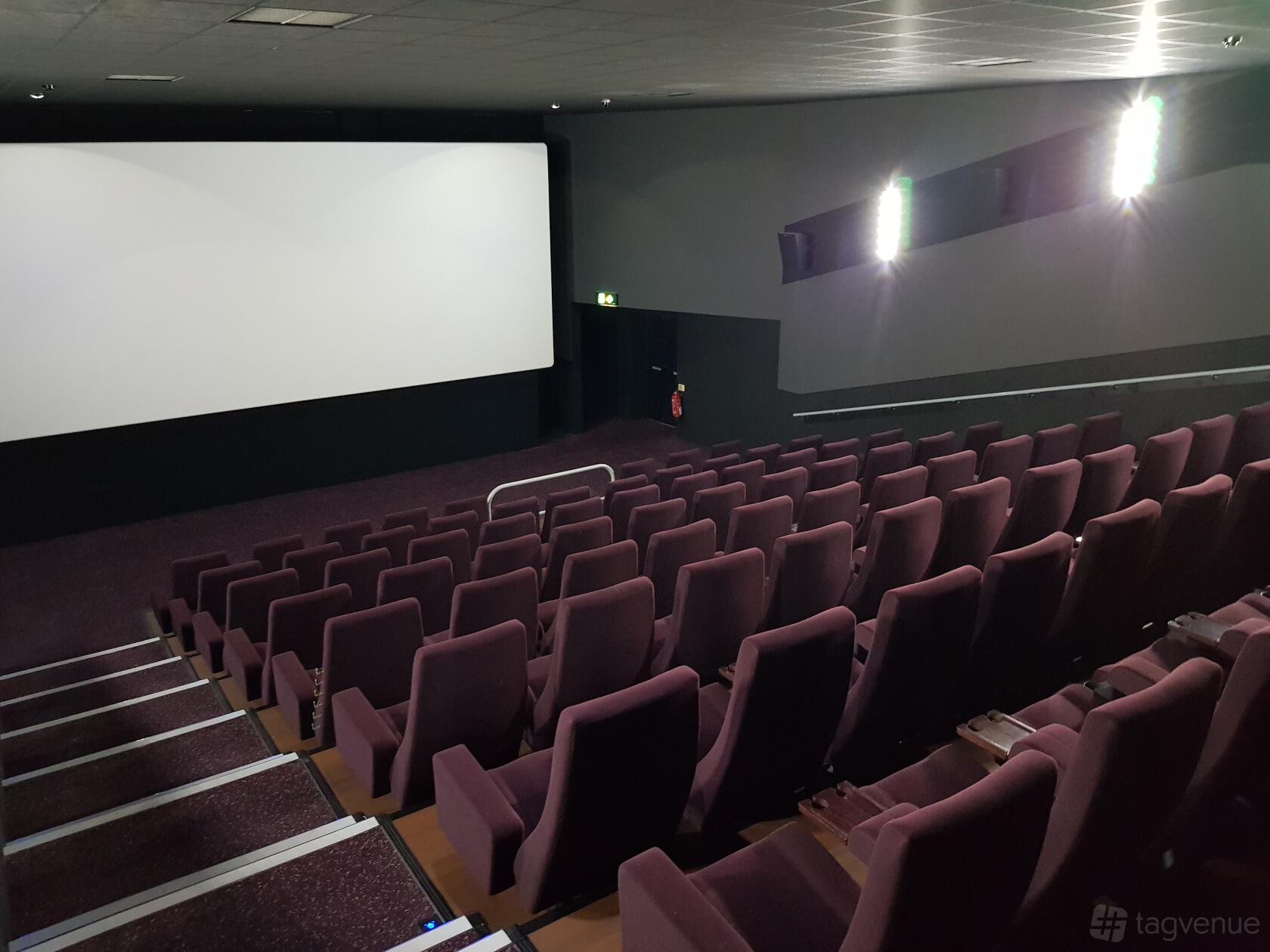 A cinema auditorium with tiered rows of purple seats facing a large projection screen at The Light Cinema Bolton.