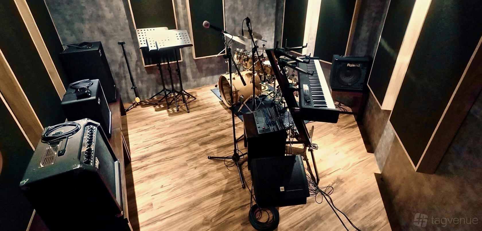 A recording studio with a drum kit, keyboard, amplifiers, and wood flooring at Tonehouse Studios.