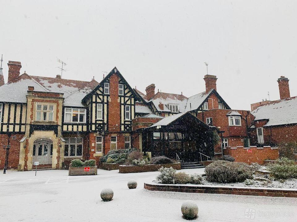 A hotel with Tudor-style timber framing, red brick walls, and a snow-covered entrance at Chesford Grange.