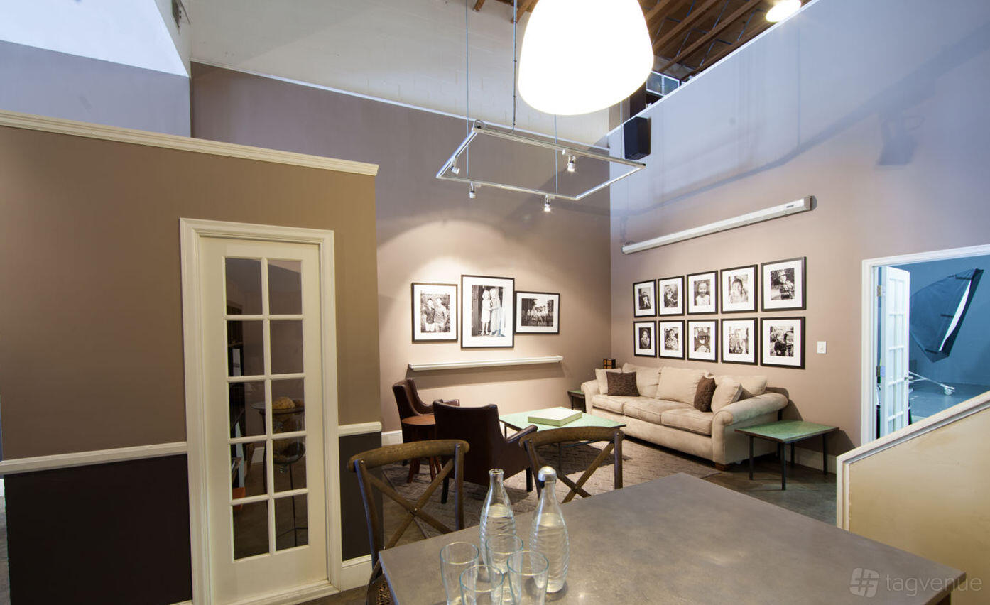A photo studio with framed black-and-white photos, a beige sofa, and exposed ceiling beams at Ets-Hokin Studios.