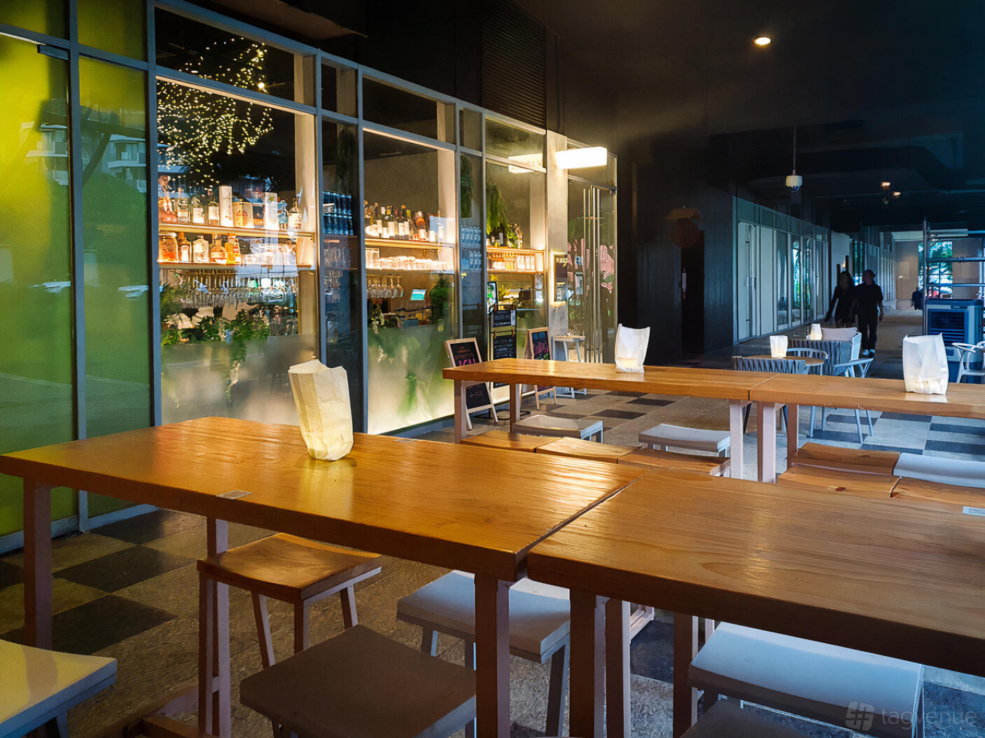 A restaurant terrace with long wooden tables, stools, and candlelit lanterns at Vibez Bistro Bar.