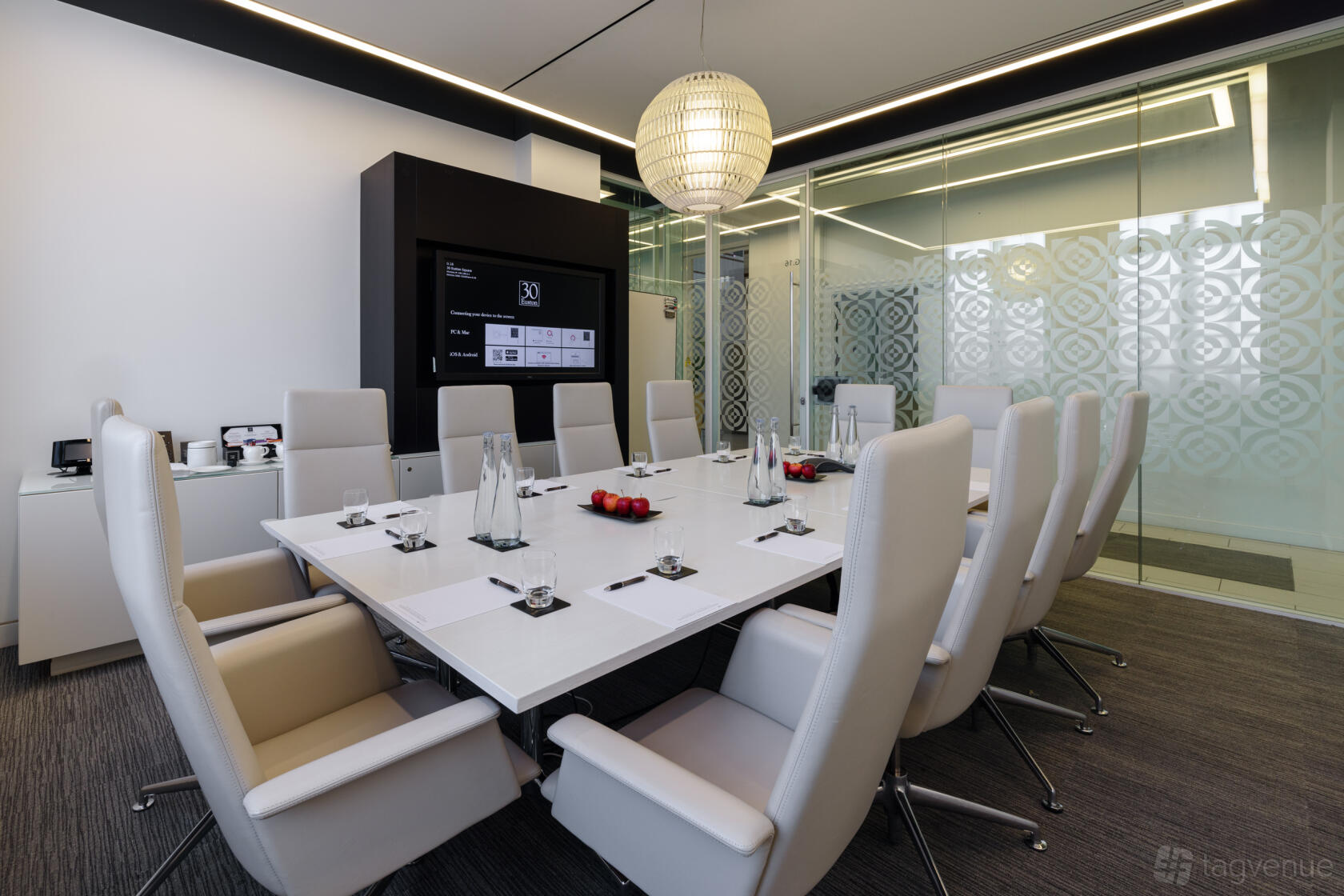 A meeting room with a long white conference table, high-back chairs, and glass partition walls at 30 Euston Square.