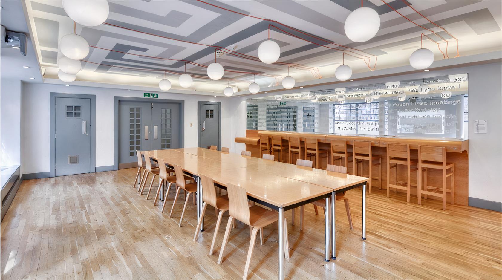 A function room with globe pendant lights, light wood flooring, and a long table with chairs at Whitechapel Gallery.