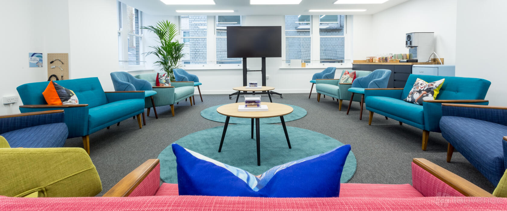 A creative space with modern lounge seating, round tables, and floor-to-ceiling windows at Wallacespace Covent Garden - 53 Parker Street.