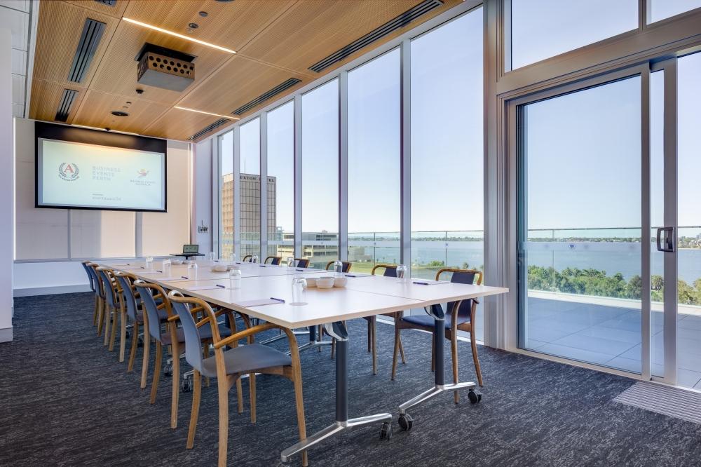 A meeting room with floor-to-ceiling windows, a boardroom table, and views of the river at The Anzac Club WA.