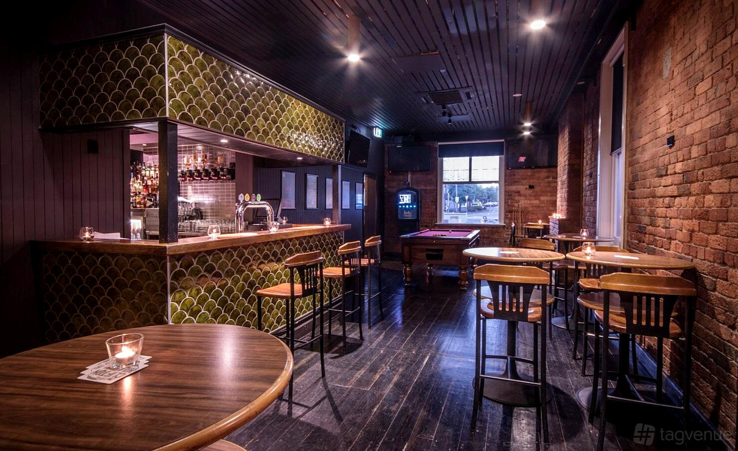 A function room in a pub with exposed brick walls, wooden tables, and a pool table at Clifton Hill Brewing.