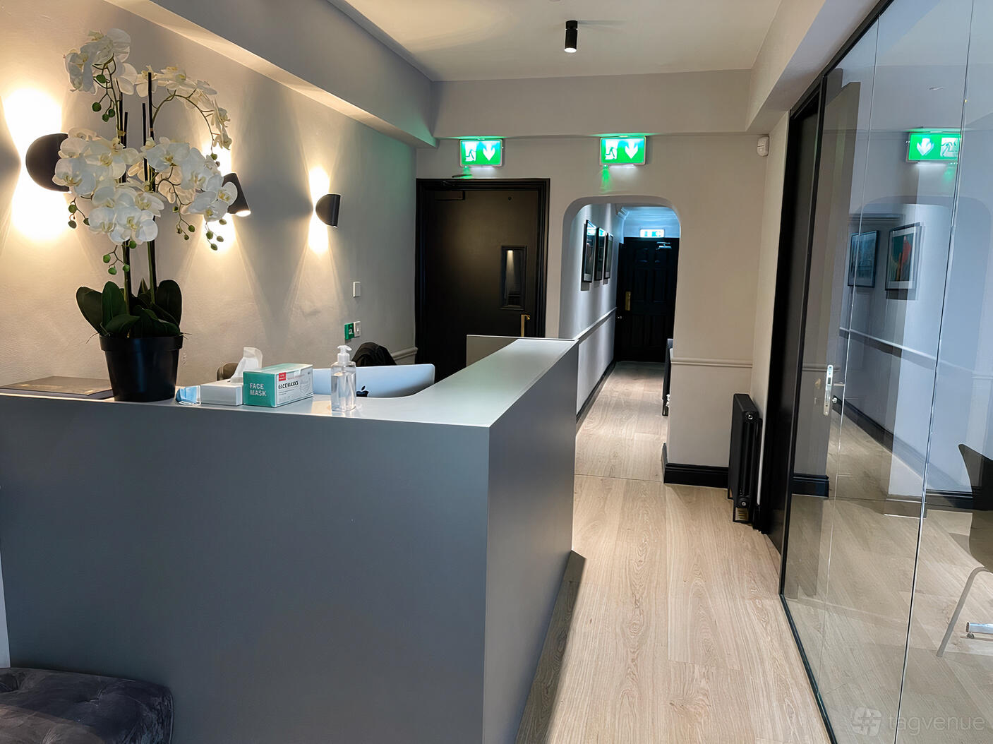 A meeting centre lobby with a reception desk, orchid arrangement, wood flooring, and glass walls at Cosmed Aesthetic Training Academy.