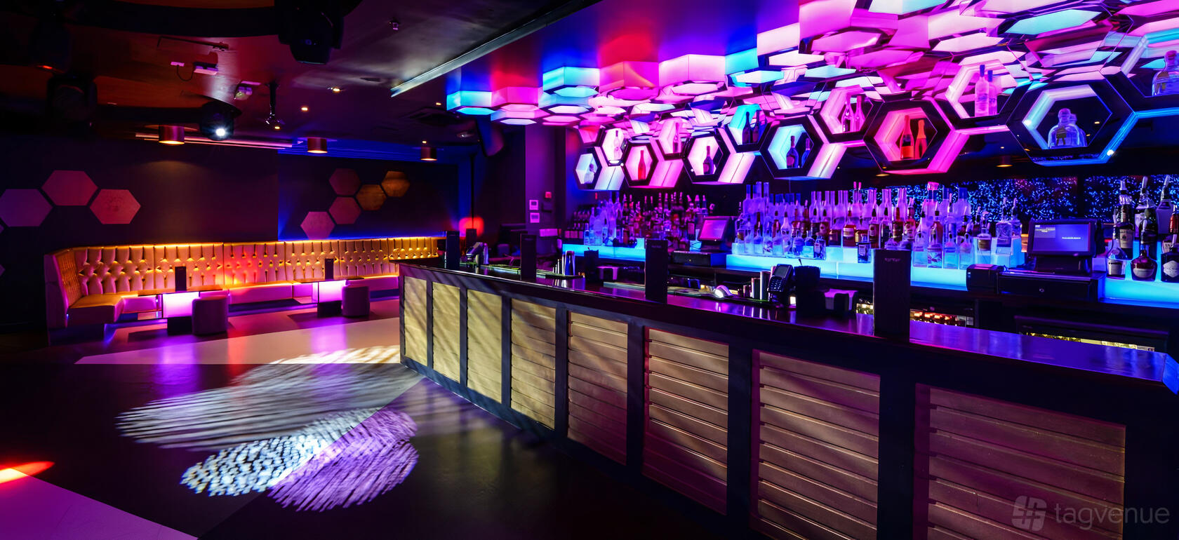 An event space in a nightclub with a geometric LED ceiling, colorful lighting, and a sleek backlit bar at LUXE.