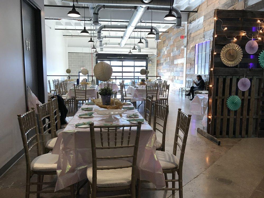 An event venue with wooden chairs, decorated tables, and exposed ductwork at Studio 52.