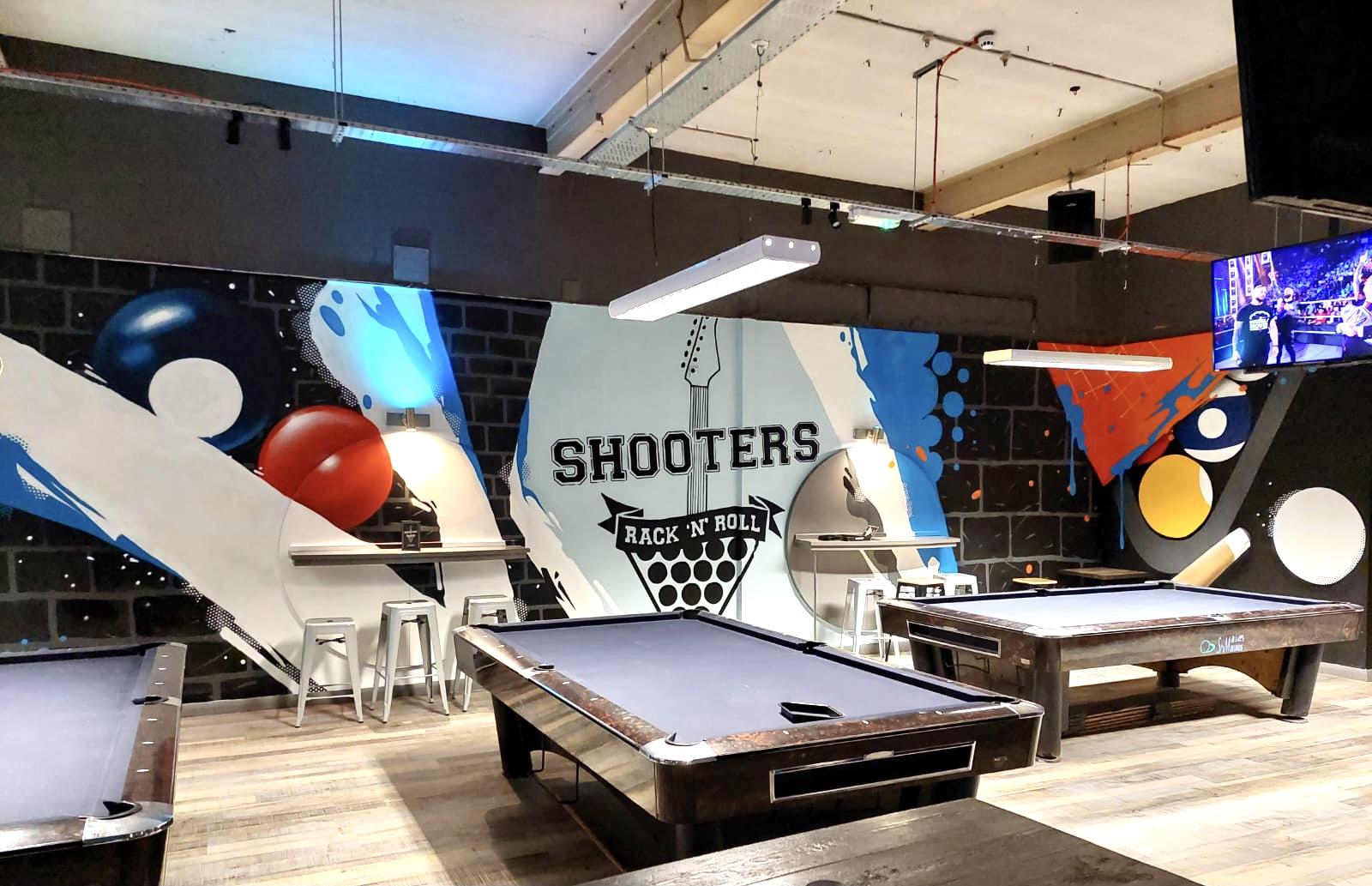 An event space in a bar with two pool tables, wall art featuring billiard balls, and bar stools at The Bierkeller Birmingham.