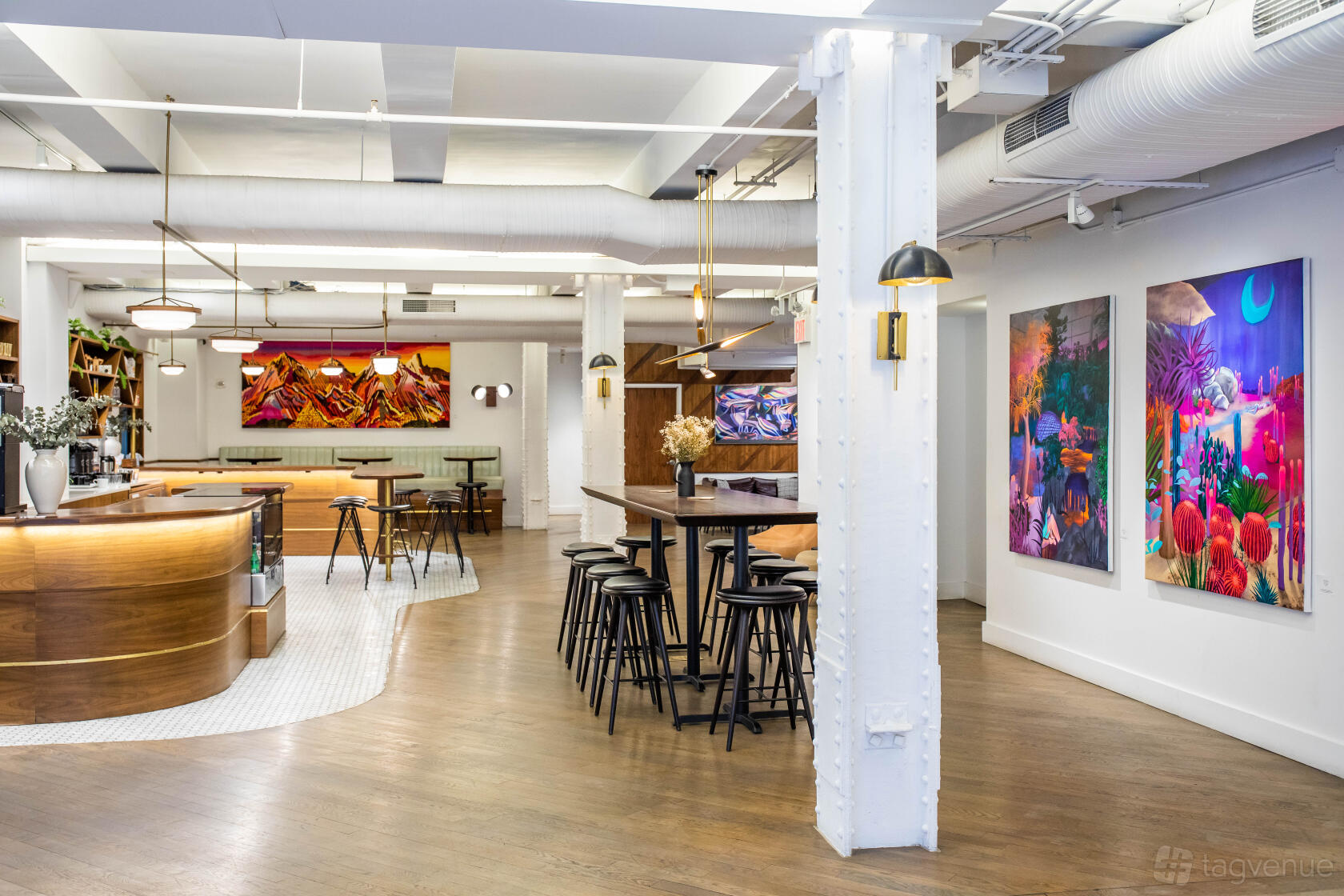 A meeting room with colorful wall art, high tables with stools, and a wood-paneled bar at Blender Space.