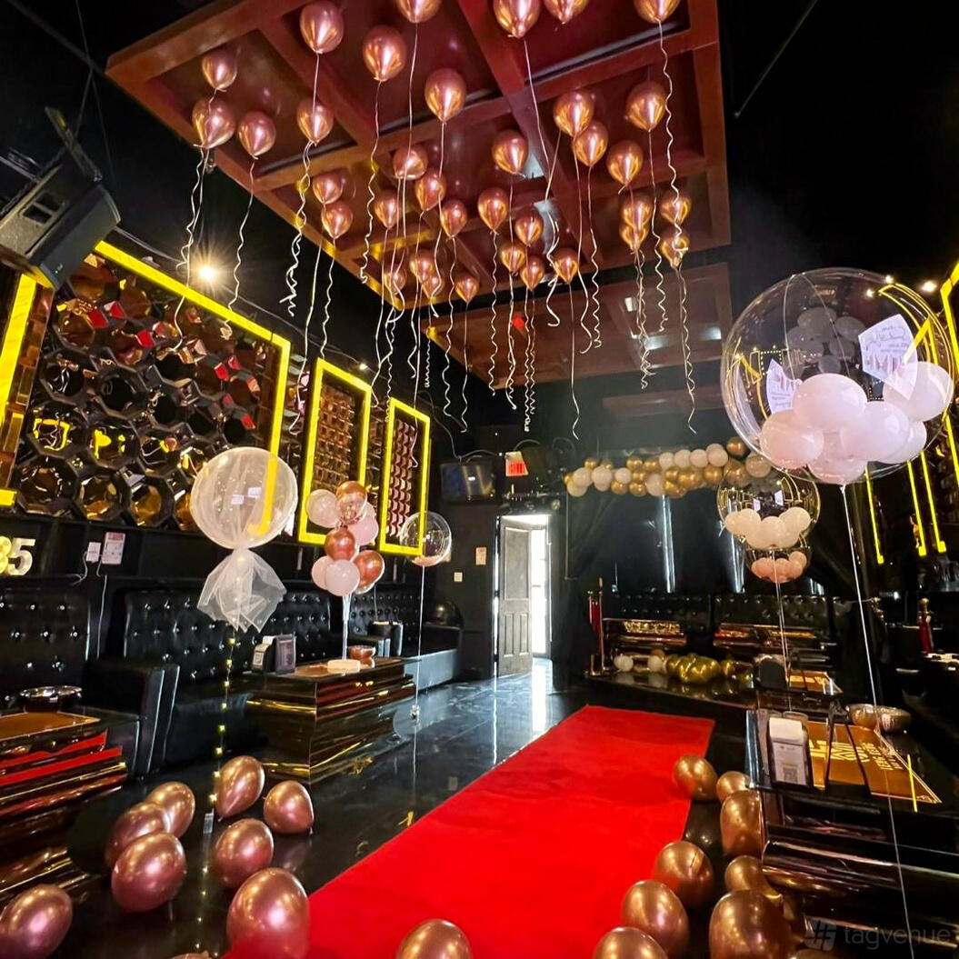 A bar with black leather seating, gold accents, mirrored walls, and metallic balloons at Leng Keng.