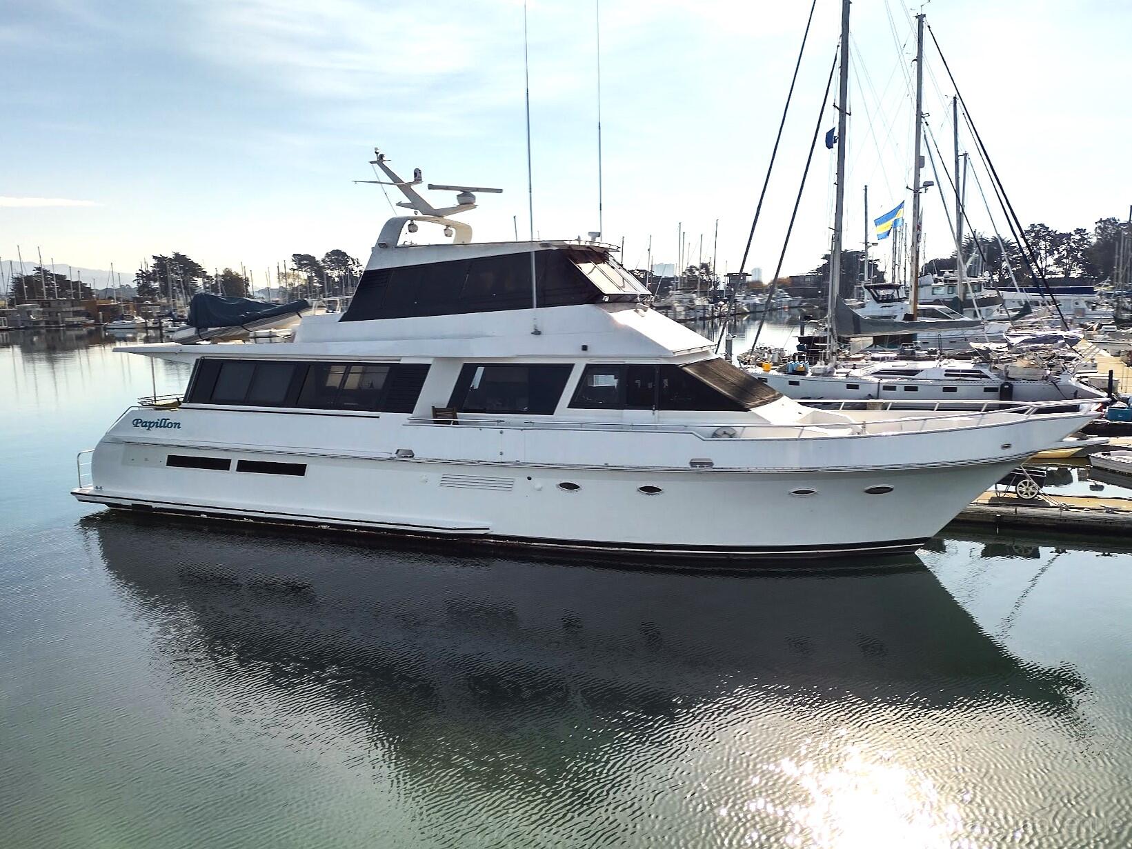 A white yacht with multiple decks docked at a marina with sailboats at Mariposa Yacht Charters.