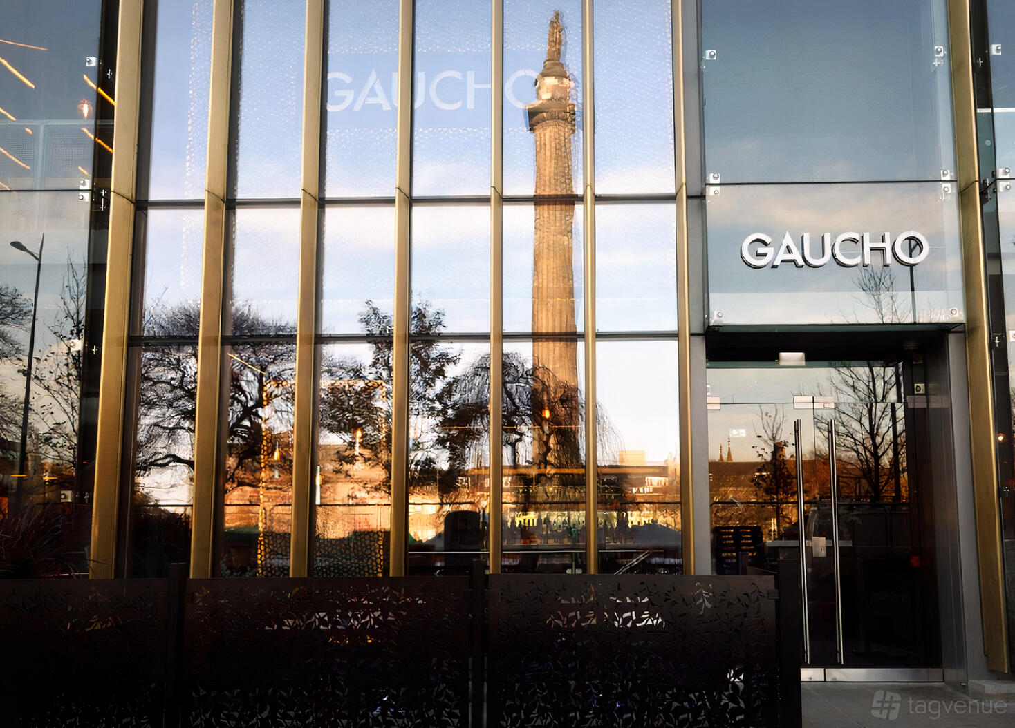 A restaurant exterior with glass facade reflecting city landmarks and trees at Gaucho Edinburgh.
