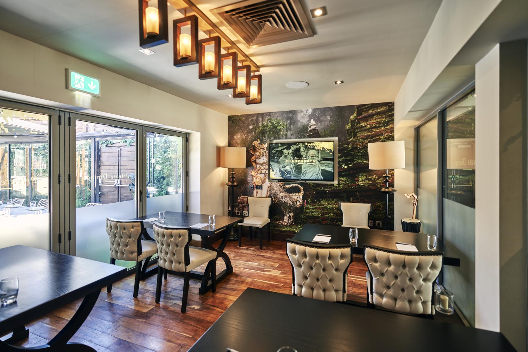 A private dining room with tufted chairs, wooden floors, and a forest mural at Chaophraya Newcastle.