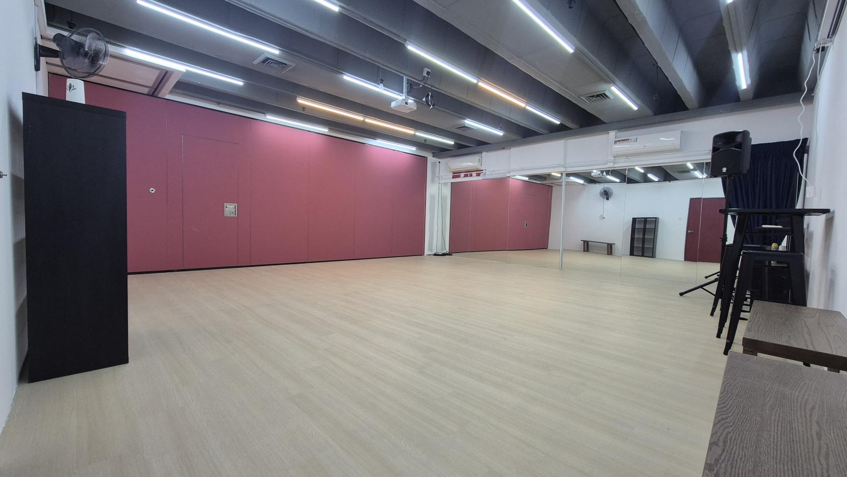 A dance studio with wood floors, pink accent walls, and ceiling strip lights at Caliente Venues @ Bugis Midland House.