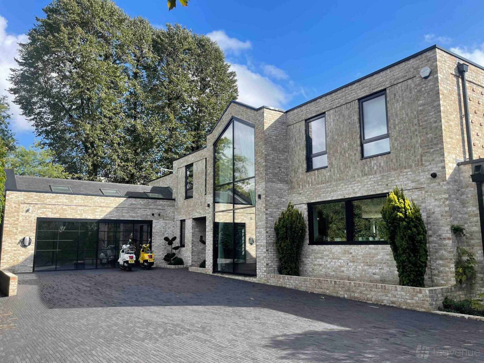 A film and photo studio with a modern brick exterior, large windows, and a paved courtyard at On Kew.