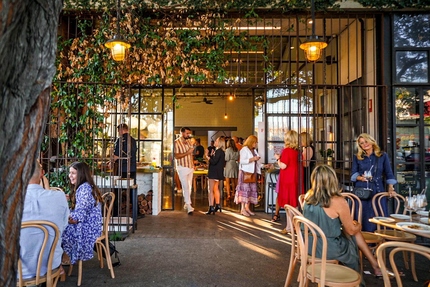 A versatile event space with open-air seating, wooden chairs, and greenery at Frontside Food & Wine.