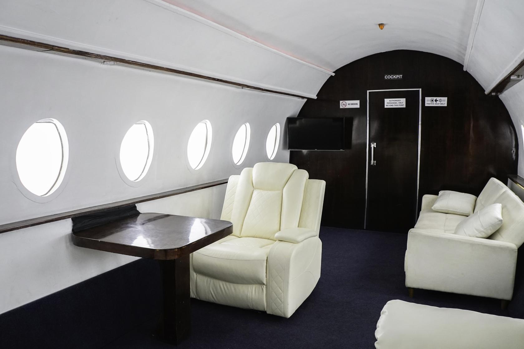 A photo studio with white leather seating, circular airplane windows, and dark wood paneling at Olympic Studios.