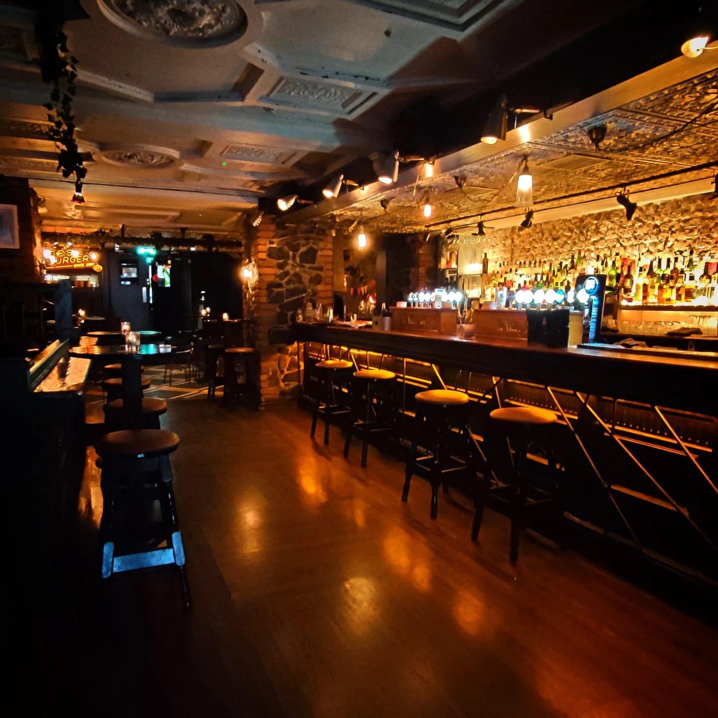 An event space in a bar with exposed stone walls, a long wooden counter, and warm ambient lighting at The Sound House.