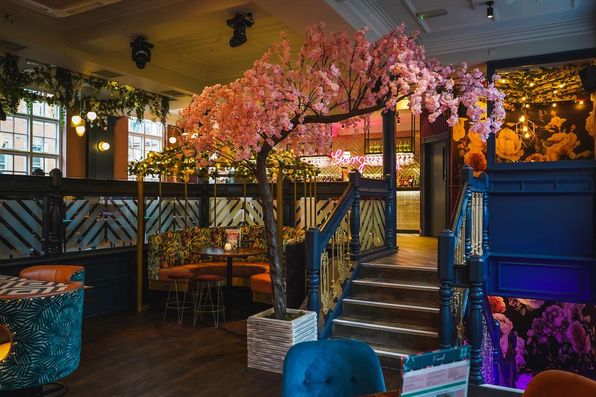A pub interior with floral wallpaper, a large artificial cherry blossom tree, and patterned seating at Slug & Lettuce Reading, Friar Street.