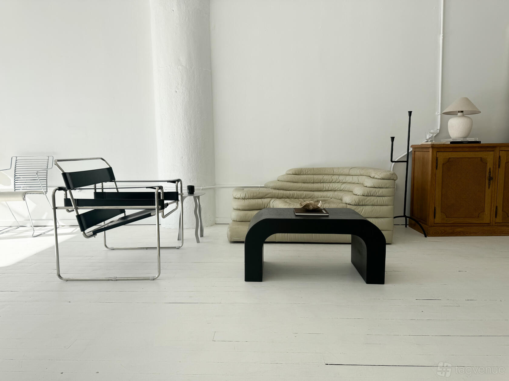 A loft photo studio with white painted floors, minimalist modern furniture, and natural lighting at Take Space.