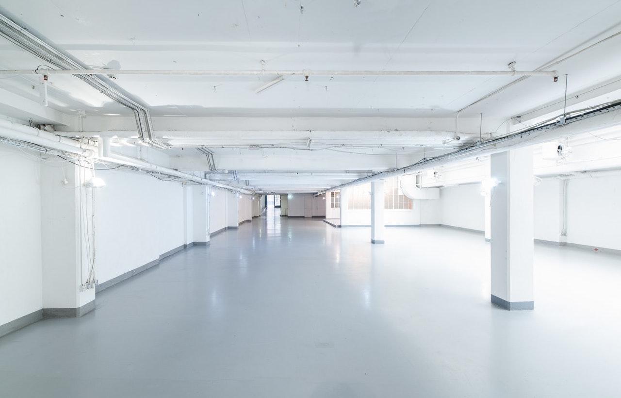 An event space with white painted walls, exposed pipes, and bright overhead lighting at The Vinyl Factory Soho.