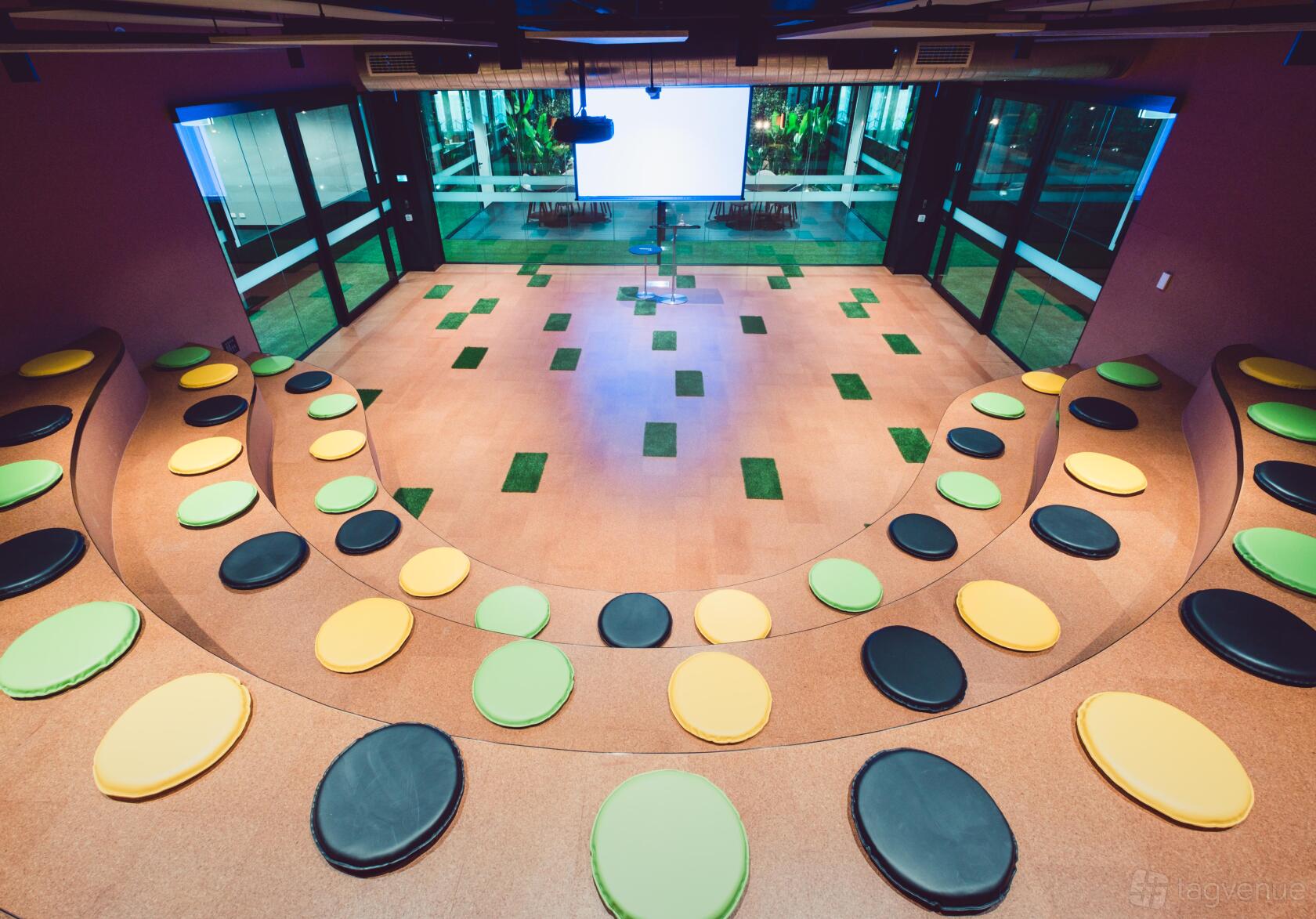 A training room with tiered seating, colorful round cushions, and large windows at Waterman at Caribbean Park.