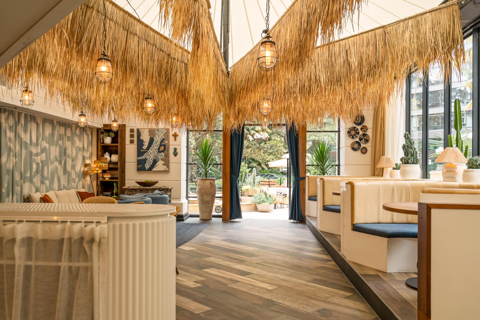 A bar with rattan pendant lights, thatched ceiling decor, and curved booth seating at Four Hundred.