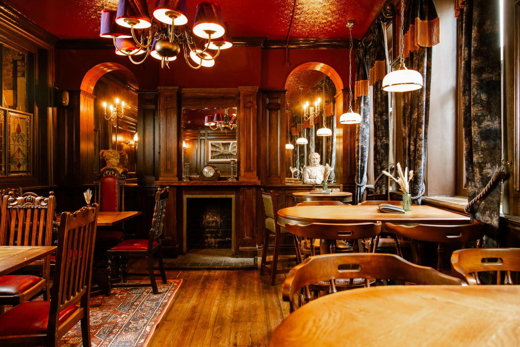 A pub dining room with wood-paneled walls, vintage chandeliers, and carved wooden chairs at Bow Street Tavern.