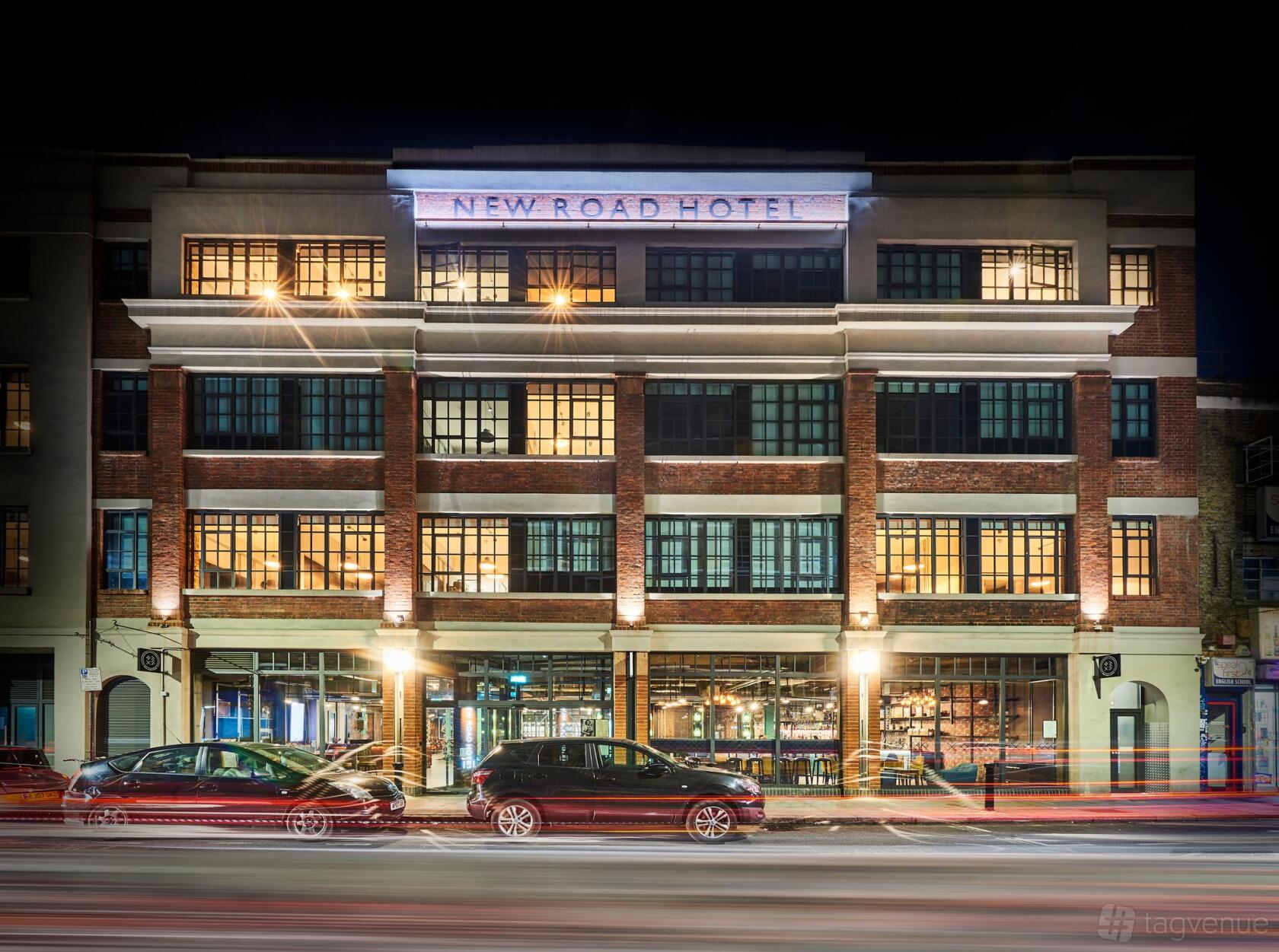 A hotel with large loft-style windows and an illuminated facade at New Road Hotel.