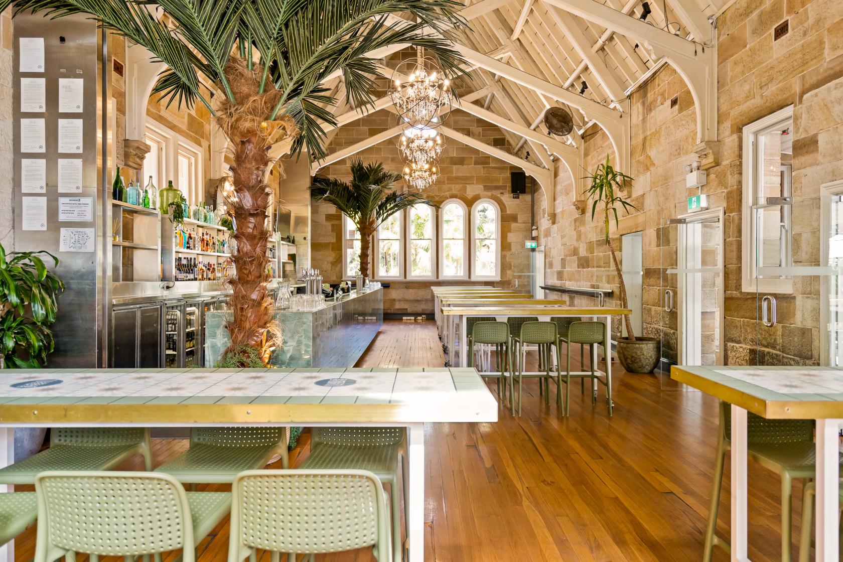 A pub with exposed stone walls, vaulted ceilings, arched windows, and a central bar at Greenwood Hotel.