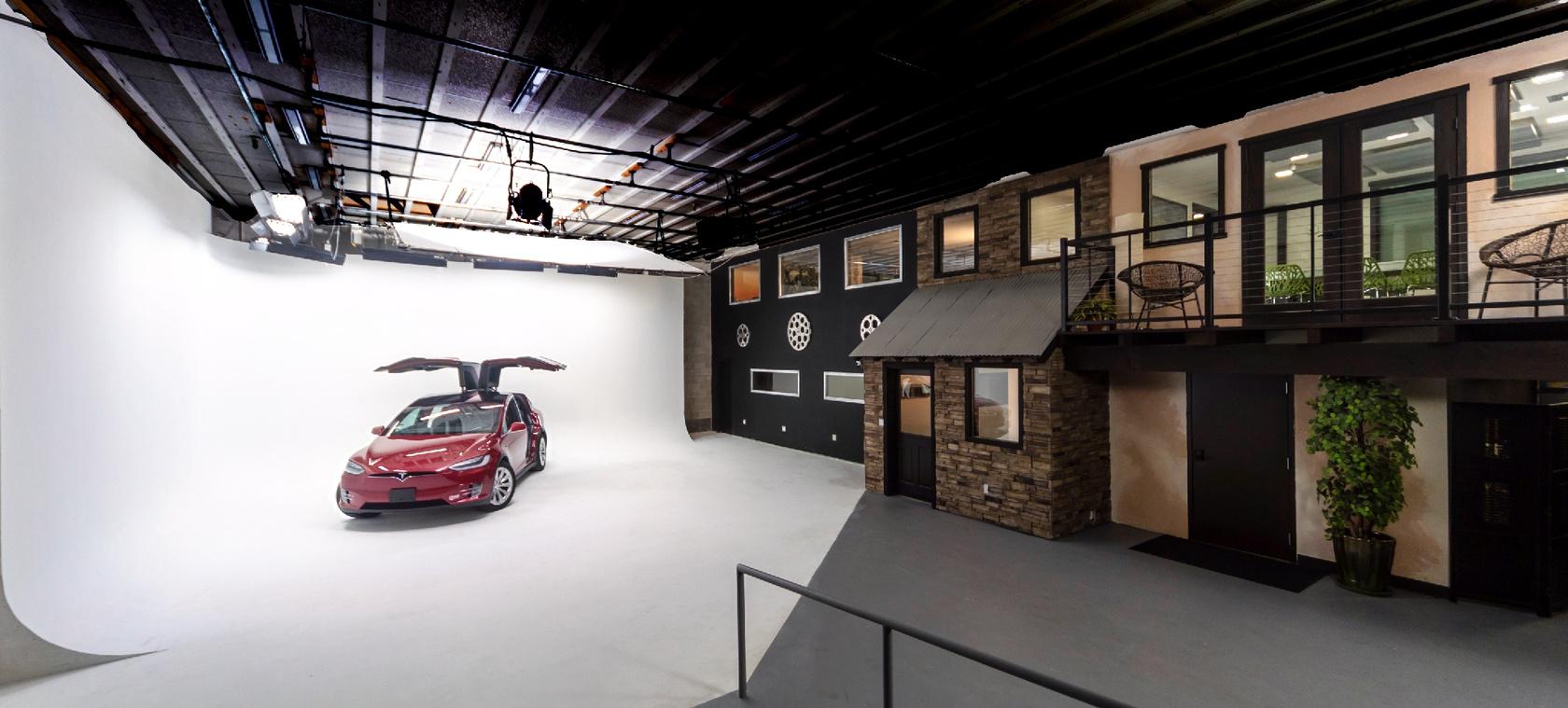 A photo studio with a seamless white cyclorama wall and a set resembling a stone building at Impact Creative.