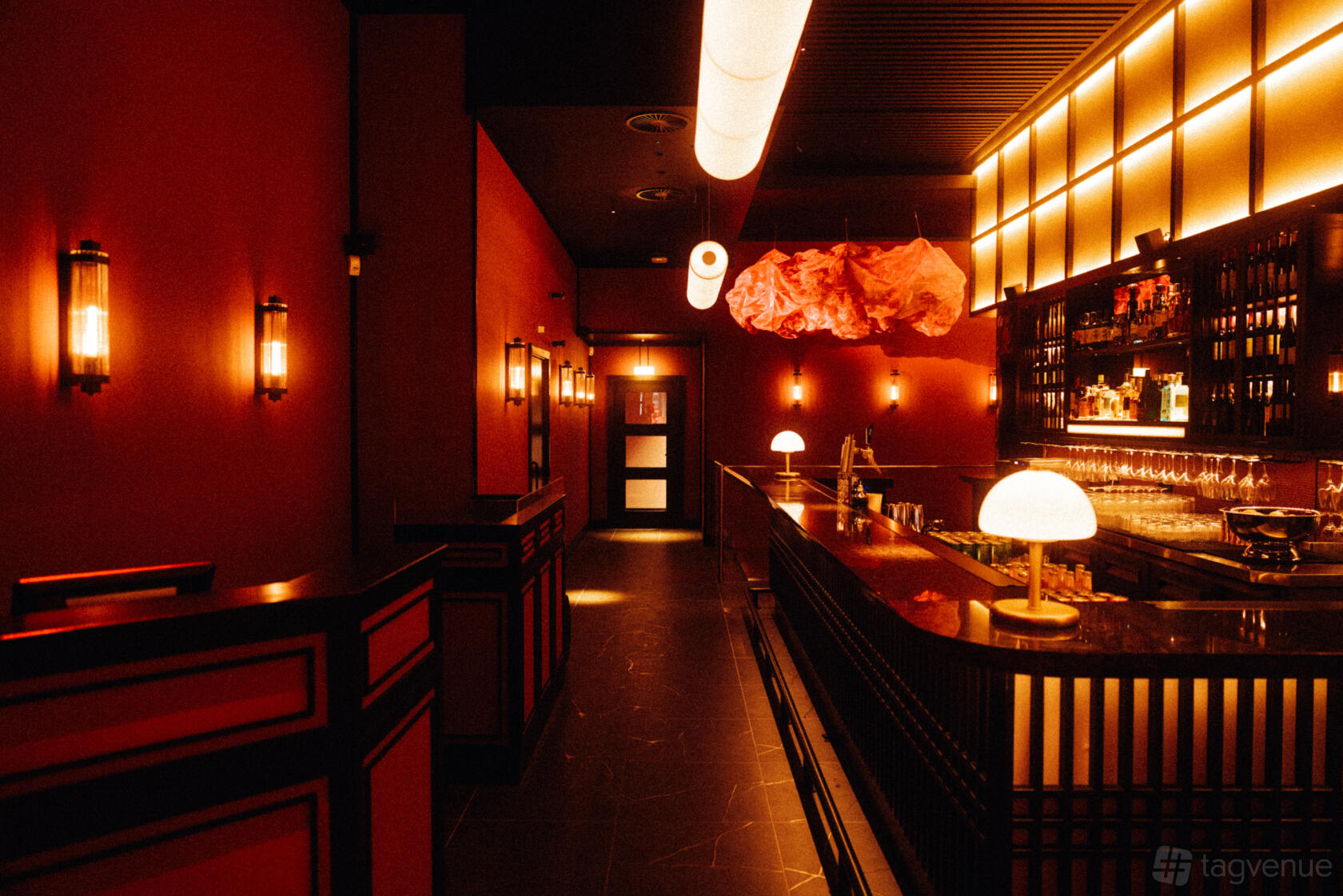 A karaoke bar with warm ambient lighting, red walls, and a backlit bar counter at Moyagi.