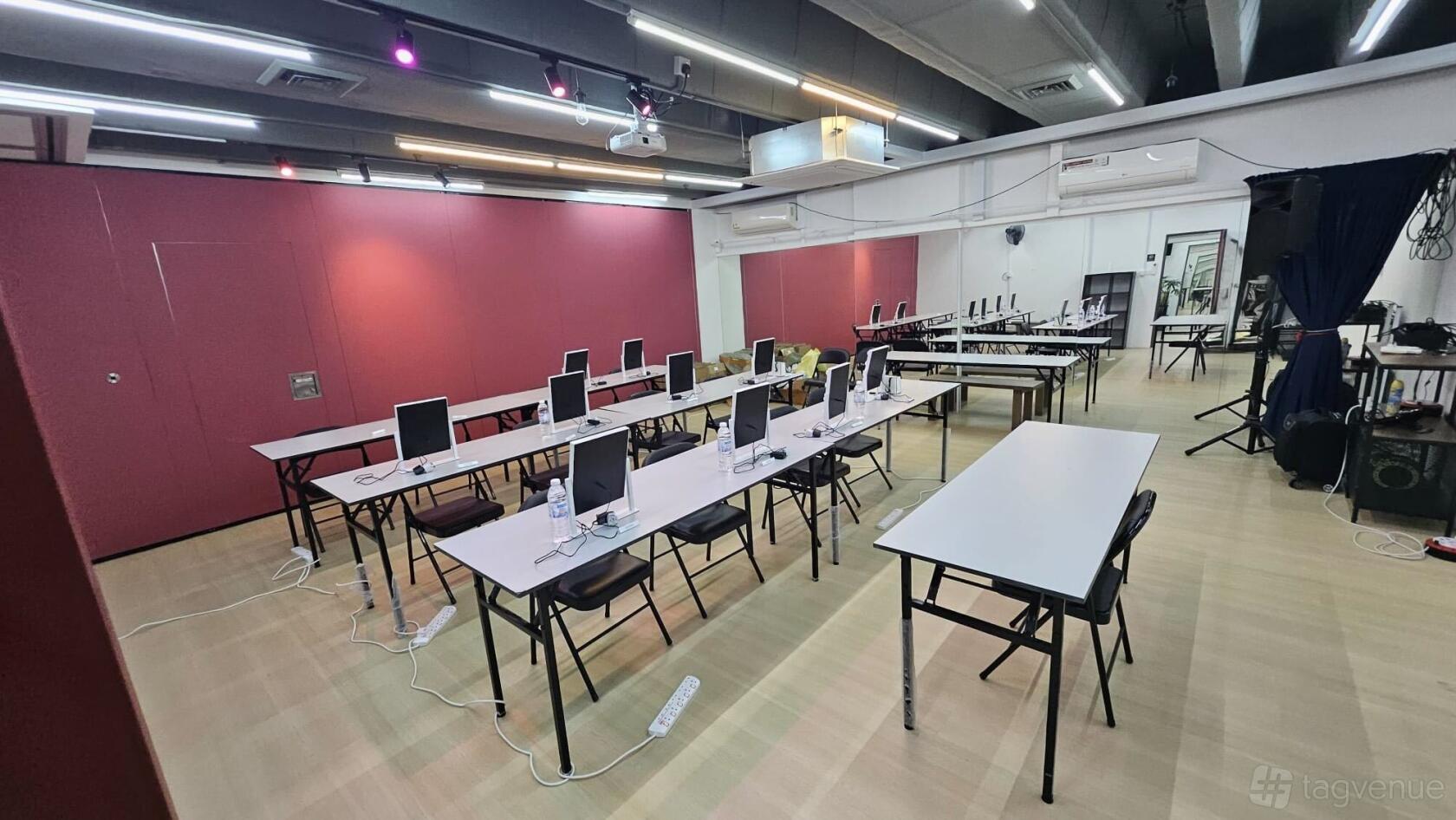 A meeting room with long tables, computers, and a light wood floor at Caliente Venues @ Bugis Midland House.