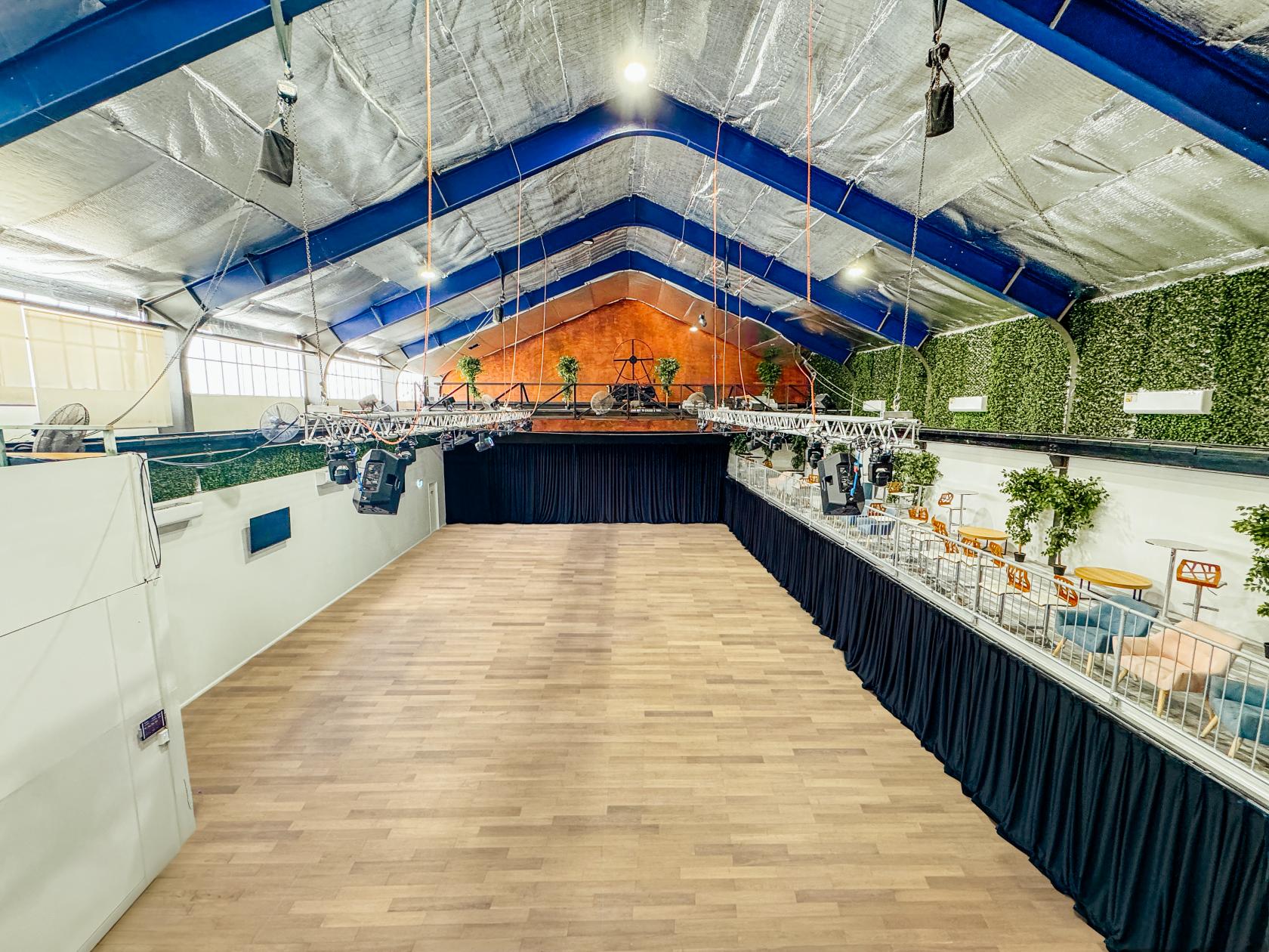 An event space in a warehouse with high ceilings, exposed beams, wood flooring, and green wall panels at 3Danks Waterloo.