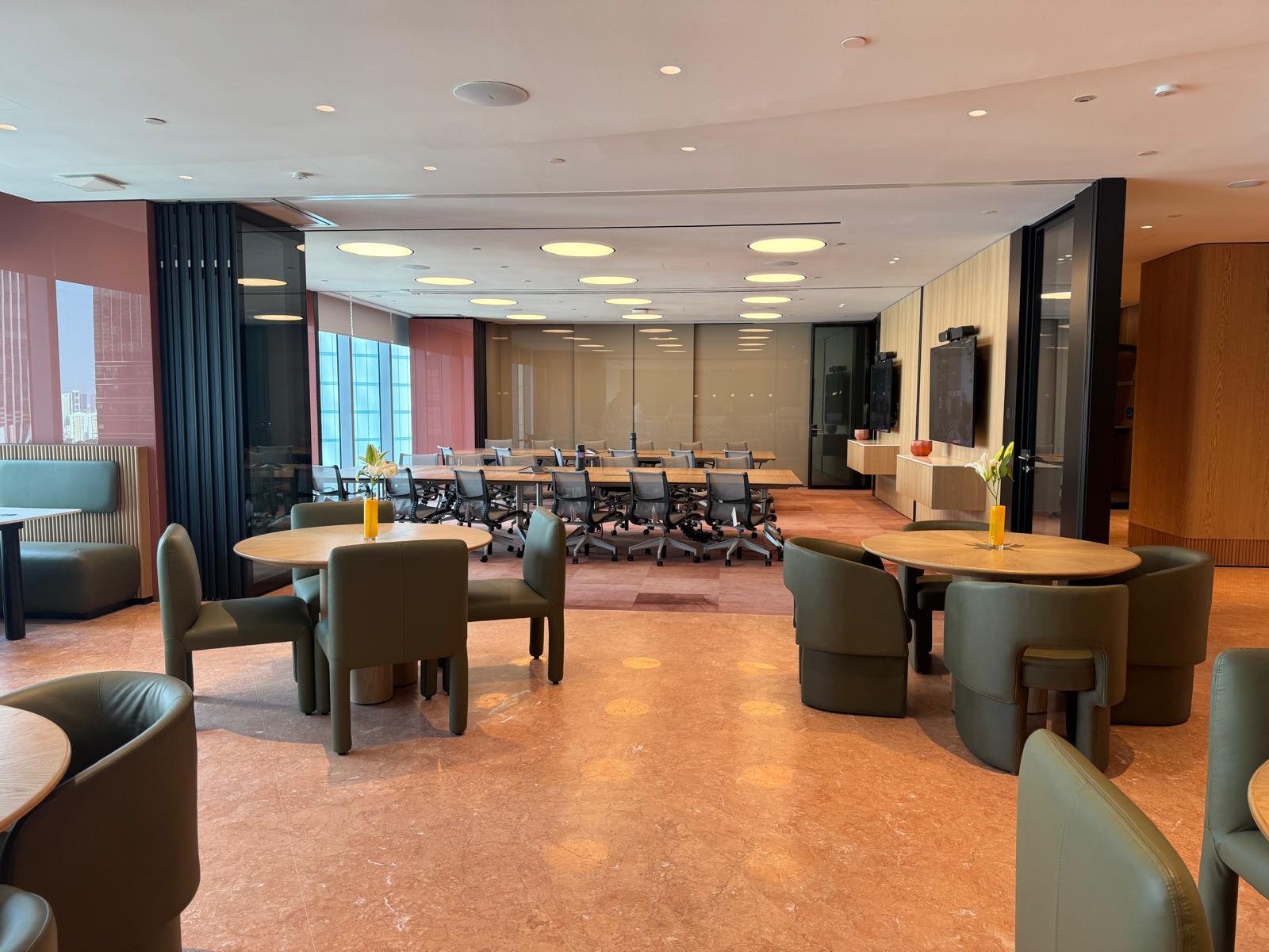 An event space with round tables, green upholstered chairs, and floor-to-ceiling windows at Ocean Financial Centre.