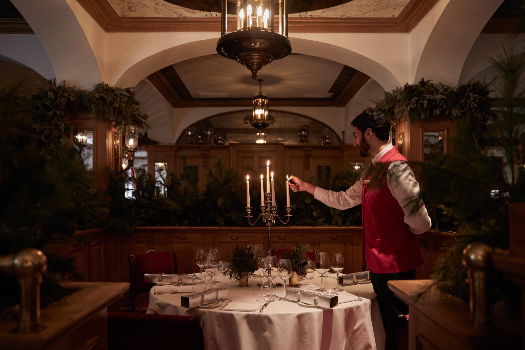 A hotel restaurant with wood-paneled walls, a round table set with a candelabra, and greenery at The Chesterfield Mayfair.